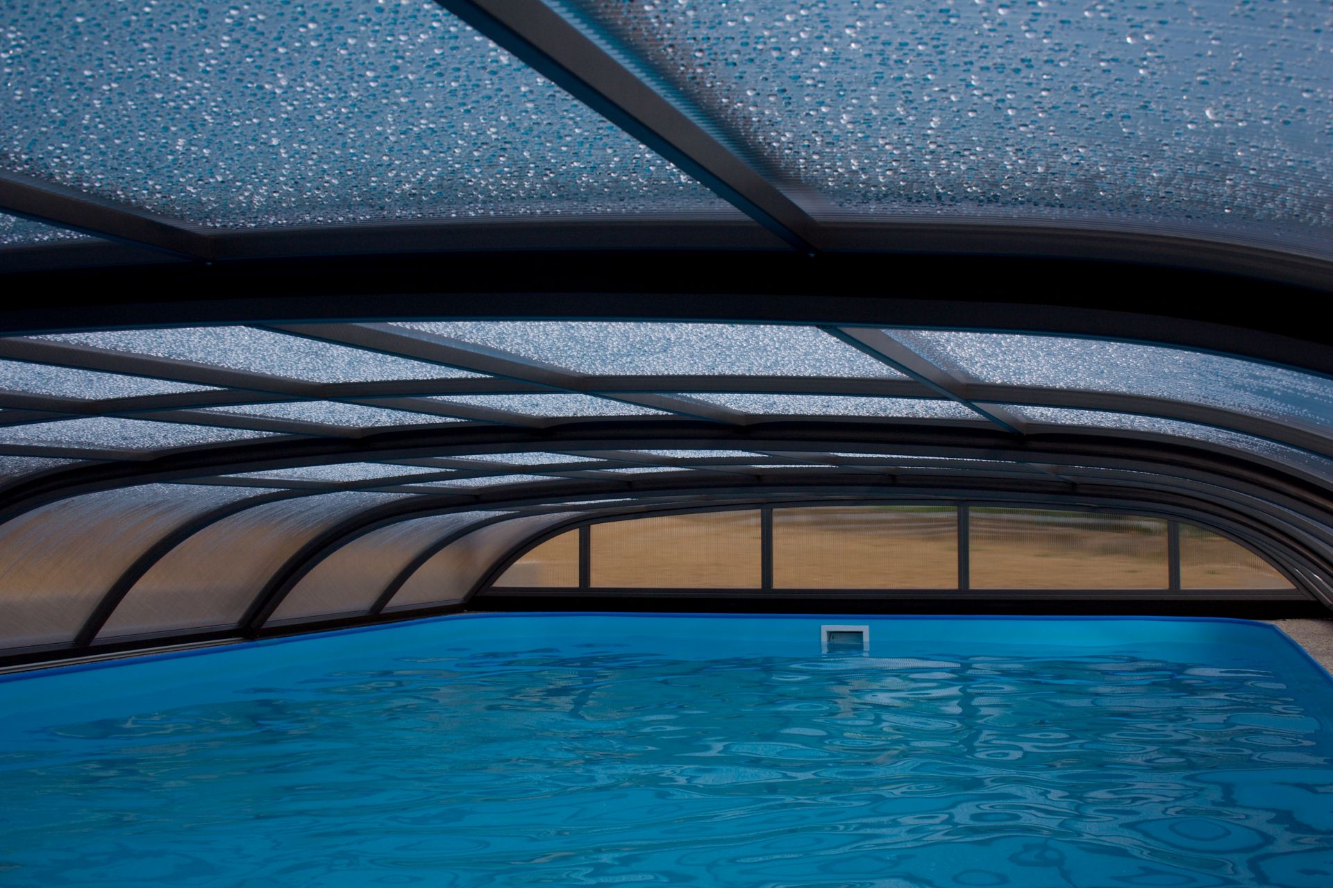 Geschlossene Poolabdeckung mit transparenter Überdachung schützt das Schwimmbecken vor Witterung und reduziert die Verdunstung