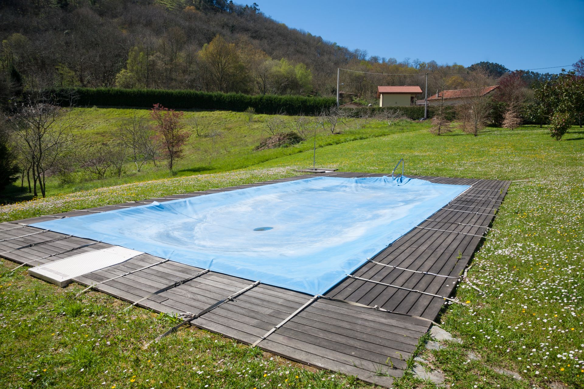 Winterfeste Poolabdeckung schützt ein rechteckiges Außenschwimmbecken vor Schmutz, Frost und Witterungseinflüssen in der kalten Jahreszeit.